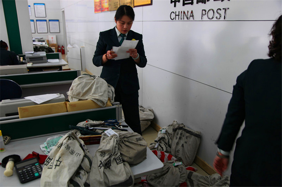 图片8:邮政支局工作人员对前台收寄的包裹快件进行核查,登记.